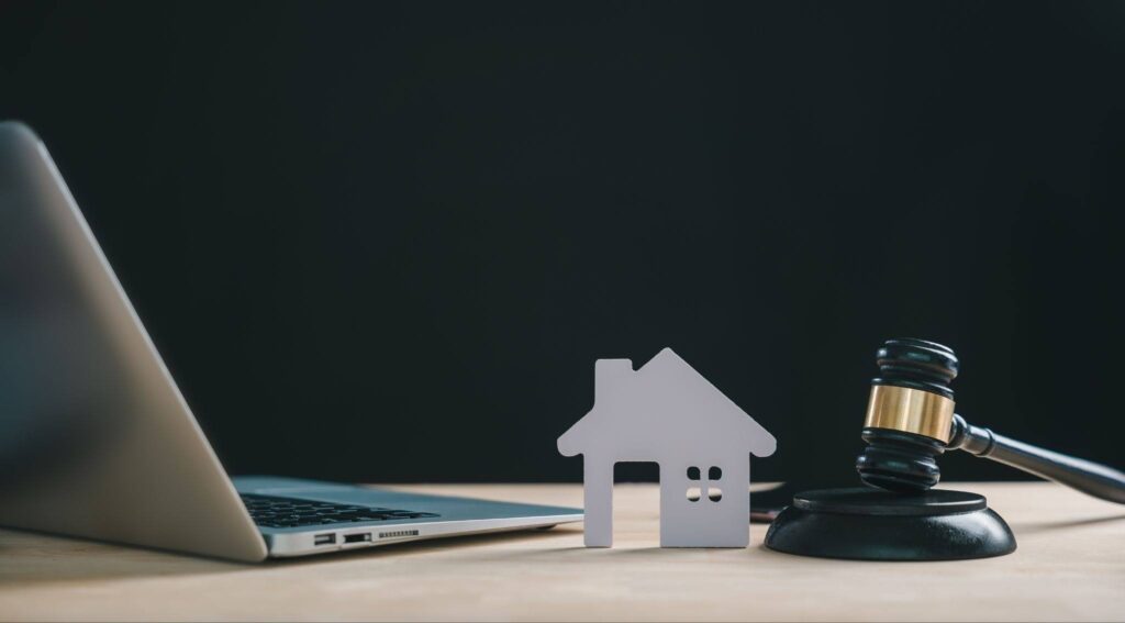 an image with a laptop, a house model, and a gavel