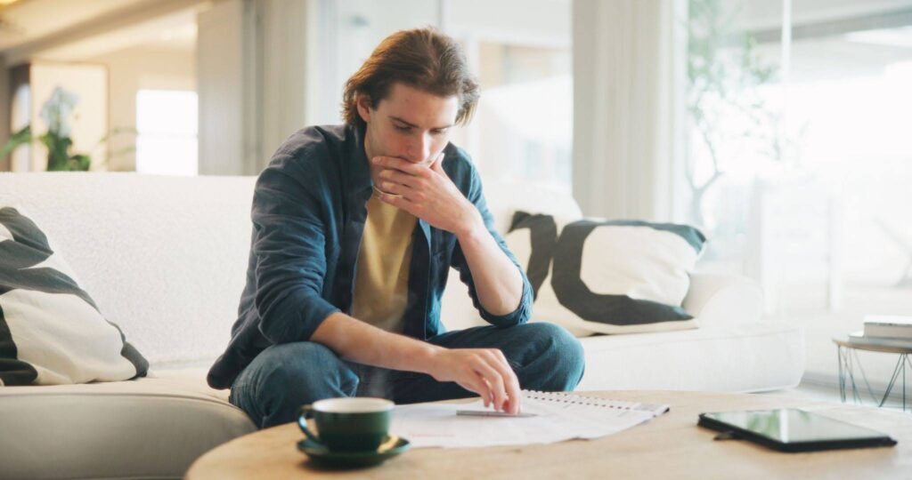 a stressed young man reading paperwork