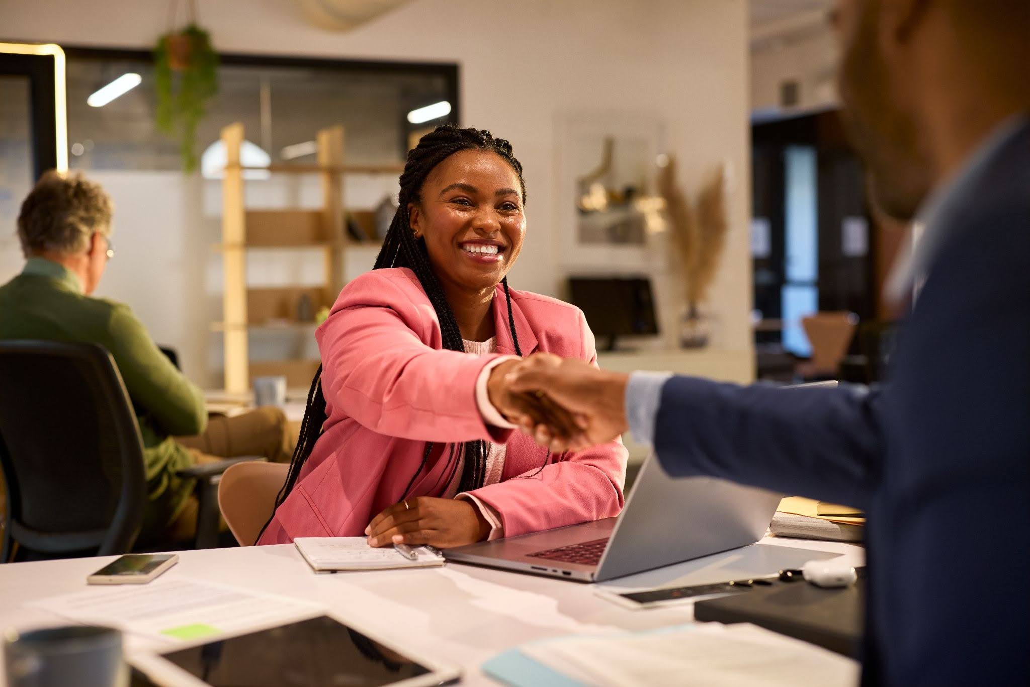 a businesswoman shaking a hand with a client in an office