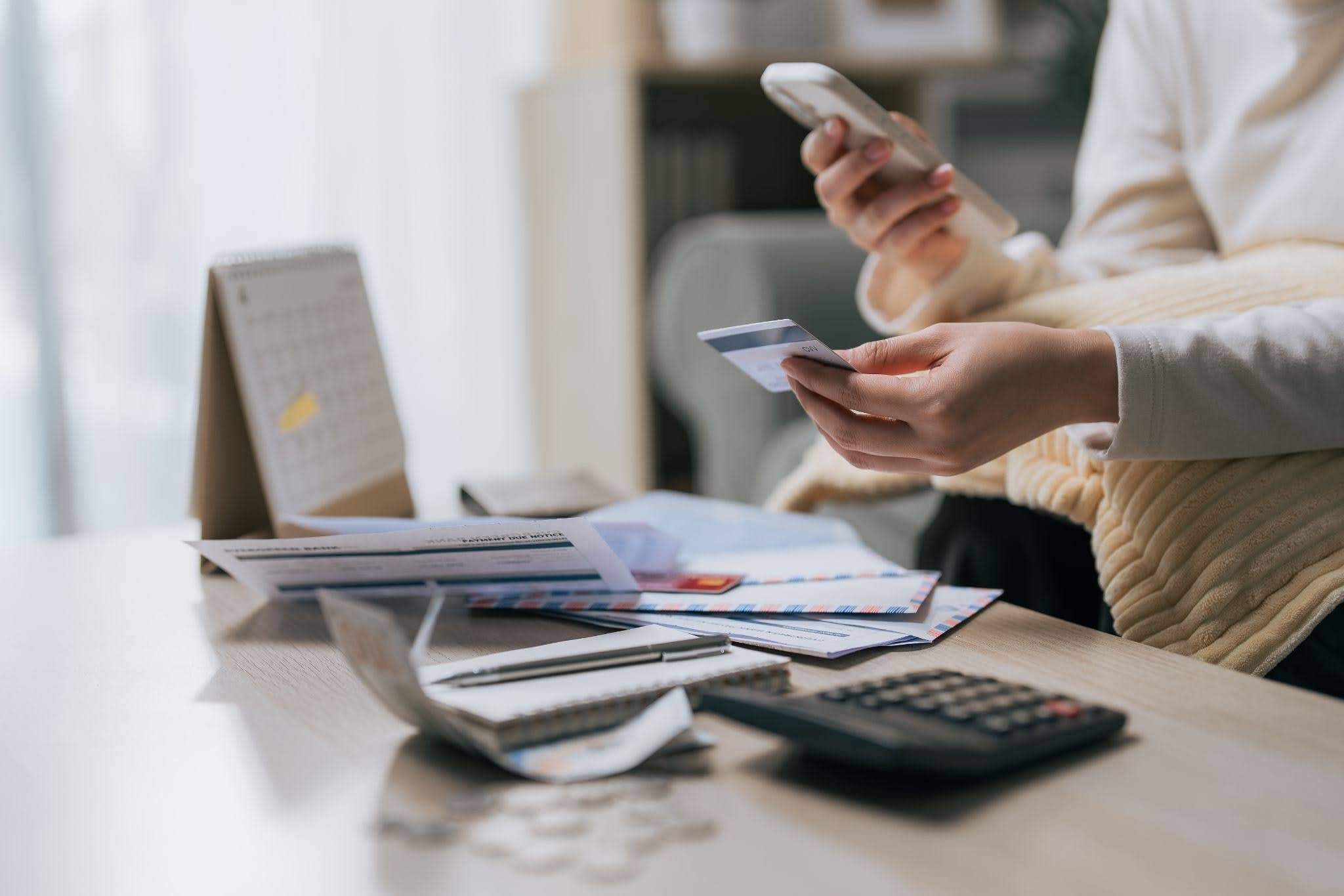 a woman holding a credit card and smartphone checking her car title loan payments